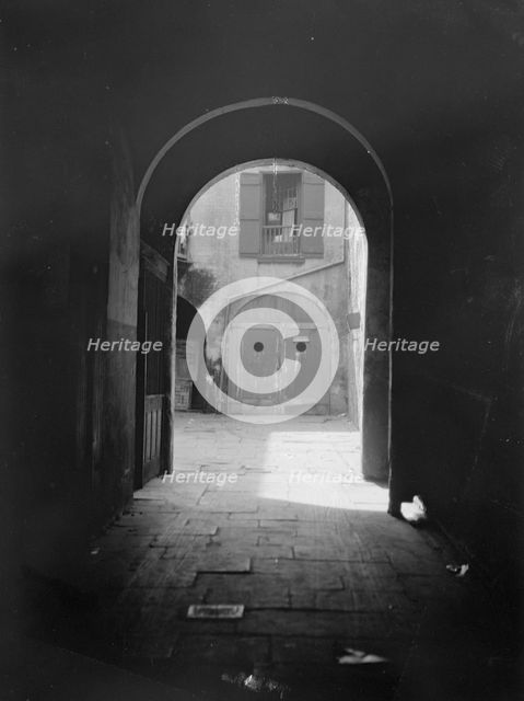 View of a courtyard through an arched passageway, New Orleans, between 1920 and 1926. Creator: Arnold Genthe.