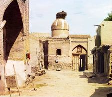 View of a courtyard, adobe buildings, and a bird's nest atop a dome, between 1905 and 1915. Creator: Sergey Mikhaylovich Prokudin-Gorsky