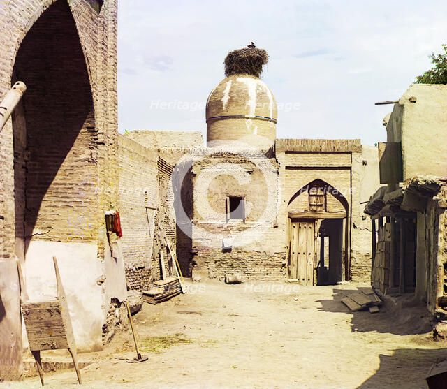View of a courtyard, adobe buildings, and a bird's nest atop a dome, between 1905 and 1915. Creator: Sergey Mikhaylovich Prokudin-Gorsky.