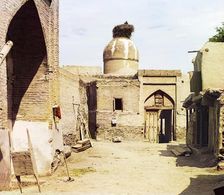 View of a courtyard, adobe buildings, and a bird's nest atop a dome, between 1905 and 1915. Creator: Sergey Mikhaylovich Prokudin-Gorsky