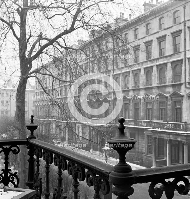 View of a lightly-snowy London square from a raised position behind a wrought-iron rail, 1947. Creator: John Gay.