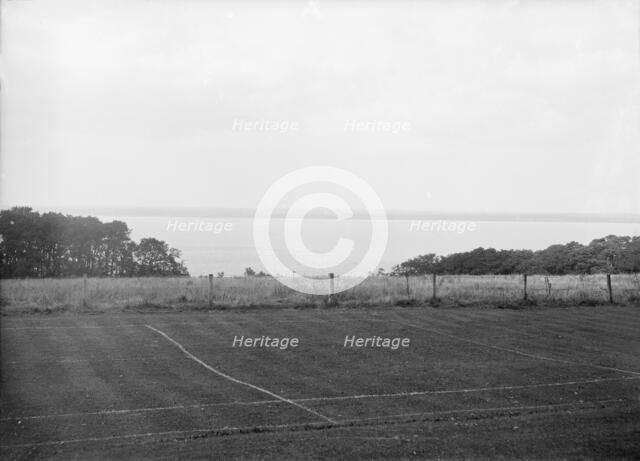 View of a tennis court and the sea, c1935. Creator: Kirk & Sons of Cowes.