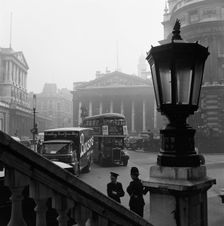 View past a lamp showing the busy traffic outside The Bank of England..., London, probably 1960s. Creator: John Gay