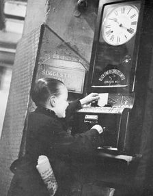 Young boy clocking on at the Trocadero Restaurant, Leicester Square, Westminster, London, c1939