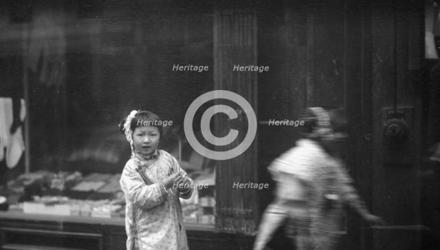 Young girl walking down the street, looking into the camera, Chinatown, San Francisco, c1896-1906. Creator: Arnold Genthe.