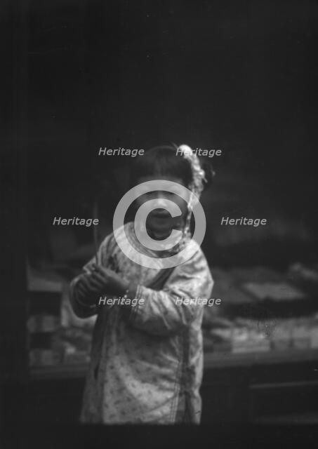 Young girl walking down the street, looking into the camera, Chinatown, San Francisco, c1896-c1906. Creator: Arnold Genthe.