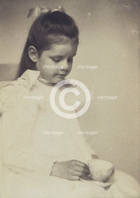 Young girl in white dress, seated holding teacup and saucer, c1900. Creator: Anne K Pilsbury.