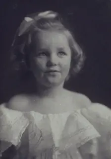 Young girl in a white off-the-shoulder dress with a ribbon in her hair , c1900. Creator: Anne K Pilsbury