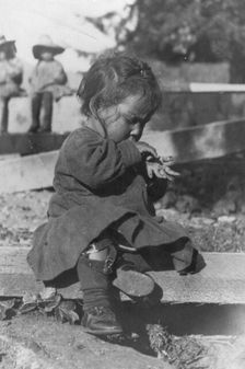 Young Eskimo child seated on board, between c1900 and c1930. Creator: Unknown