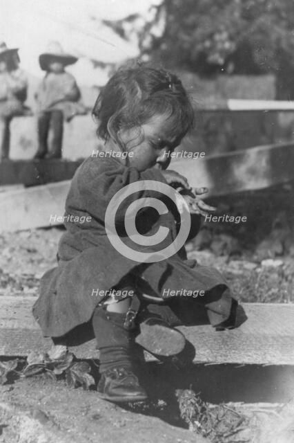 Young Eskimo child seated on board, between c1900 and c1930. Creator: Unknown.