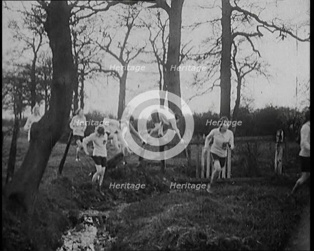 Young Female Civilians Wearing Sport Outfits Running Across a Field Jumping over Water in a..., 1920 Creator: British Pathe Ltd.