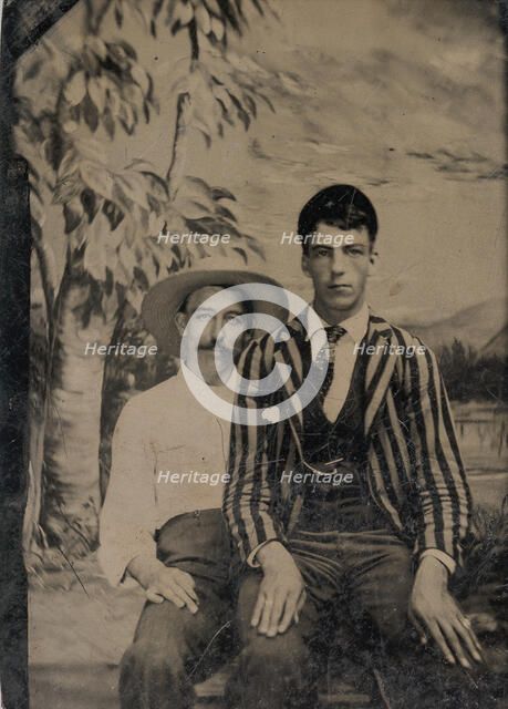 Young Man in a Striped Jacket, Sitting on the Lap of Another Man in Front of Painted..., 1860s-80s. Creator: Unknown.