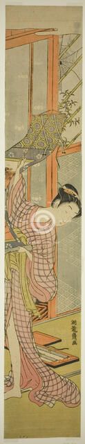 Young Woman Hanging a Painting, c. 1771. Creator: Isoda Koryusai.