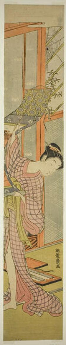 Young Woman Hanging a Painting, c. 1771. Creator: Isoda Koryusai