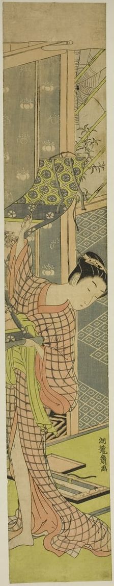 Young Woman Hanging a Painting, c. 1771. Creator: Isoda Koryusai