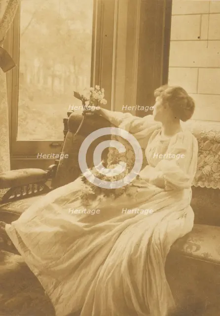 Young woman seated by a window with flowers in her lap, c1900. Creator: Mary A. Bartlett.