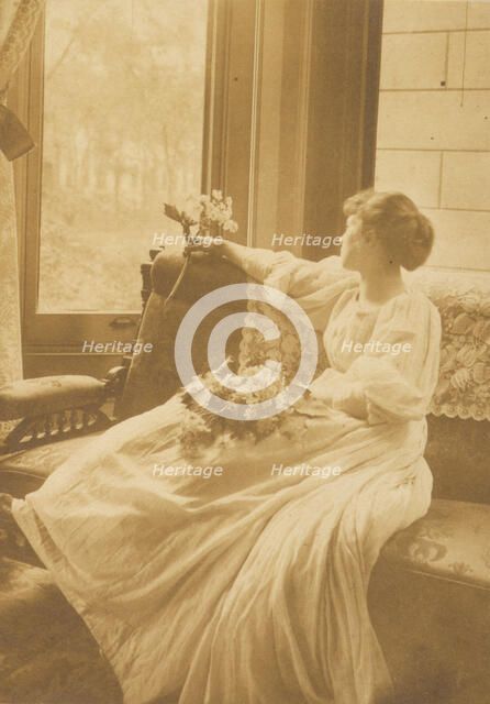 Young woman seated by a window with flowers in her lap, c1900. Creator: Mary A. Bartlett.