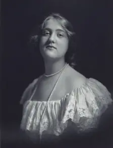 Young woman wearing an off-the-shoulder dress and long pearl necklace, looking front..., c1900. Creator: F. Gercher