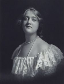 Young woman wearing an off-the-shoulder dress and long pearl necklace, looking front..., c1900. Creator: F. Gercher
