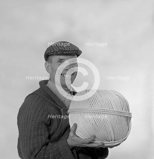 Yorkshireman wearing a flat cap and holding a large ball of twine, 1968. Creator: Michael Walters.