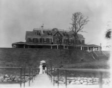 Yacht club, Oyster Bay, Long Island, N.Y. Couple walking on far end of bridge or pier, 1905. Creator: Frances Benjamin Johnston