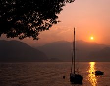 Yacht at sunset, Lake Maggiore, Italy. Creator: Peter Thompson