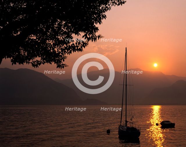 Yacht at sunset, Lake Maggiore, Italy. Creator: Peter Thompson.