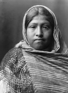 Yaqui girl, head-and-shoulders portrait, facing front, with striped shawl draped around..., c1907. Creator: Edward Sheriff Curtis