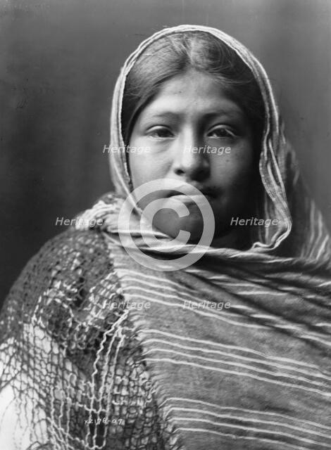 Yaqui girl, head-and-shoulders portrait, facing front, with striped shawl draped around..., c1907. Creator: Edward Sheriff Curtis.