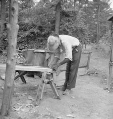 Zollie Lyons repairing the tobacco sleds at...harvest season, Wake County, North Carolina, 1939. Creator: Dorothea Lange